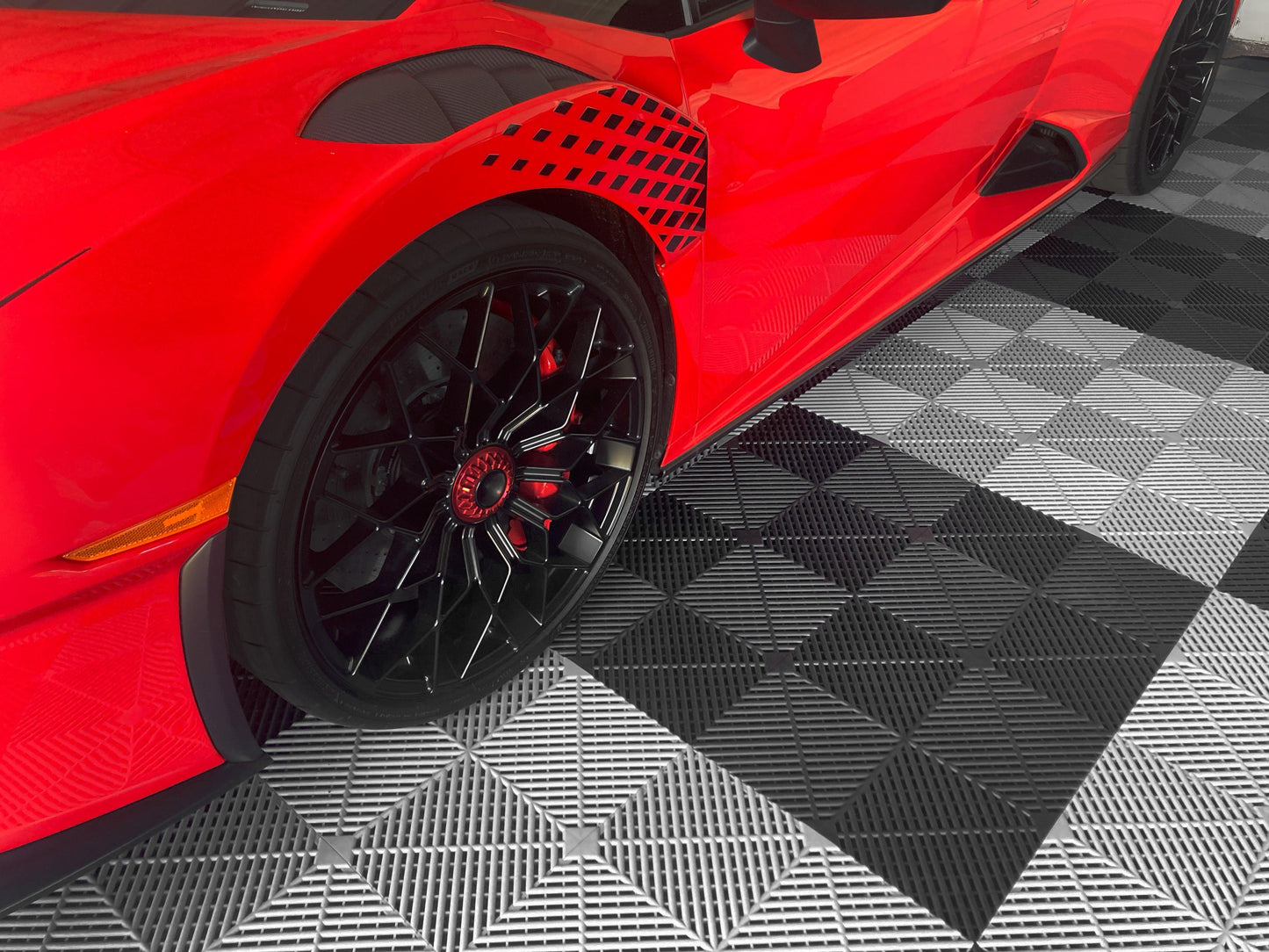Red car parked on white and black garage floor tiles