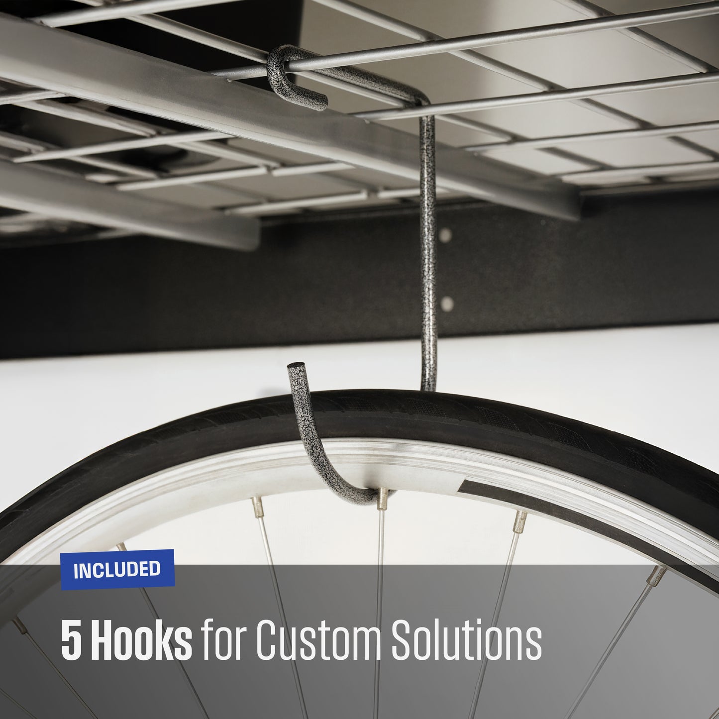 Close-up of a textured grey metal hook hanging from a garage shelf, with a bicycle tire partially visible to demonstrate use. Text overlay reads 'INCLUDED 5 Hooks for Custom Solutions'.
