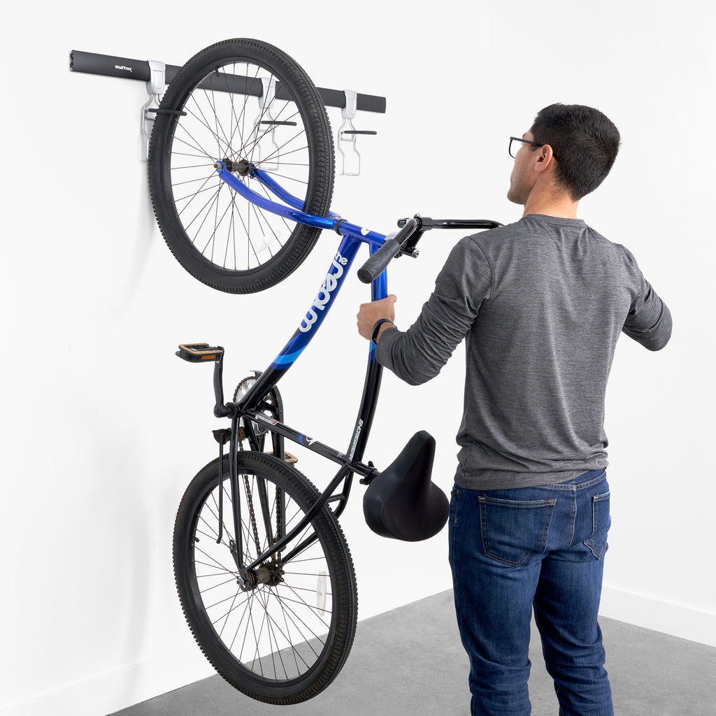 person hanging a bicycle from a garage track system (7726746599638)