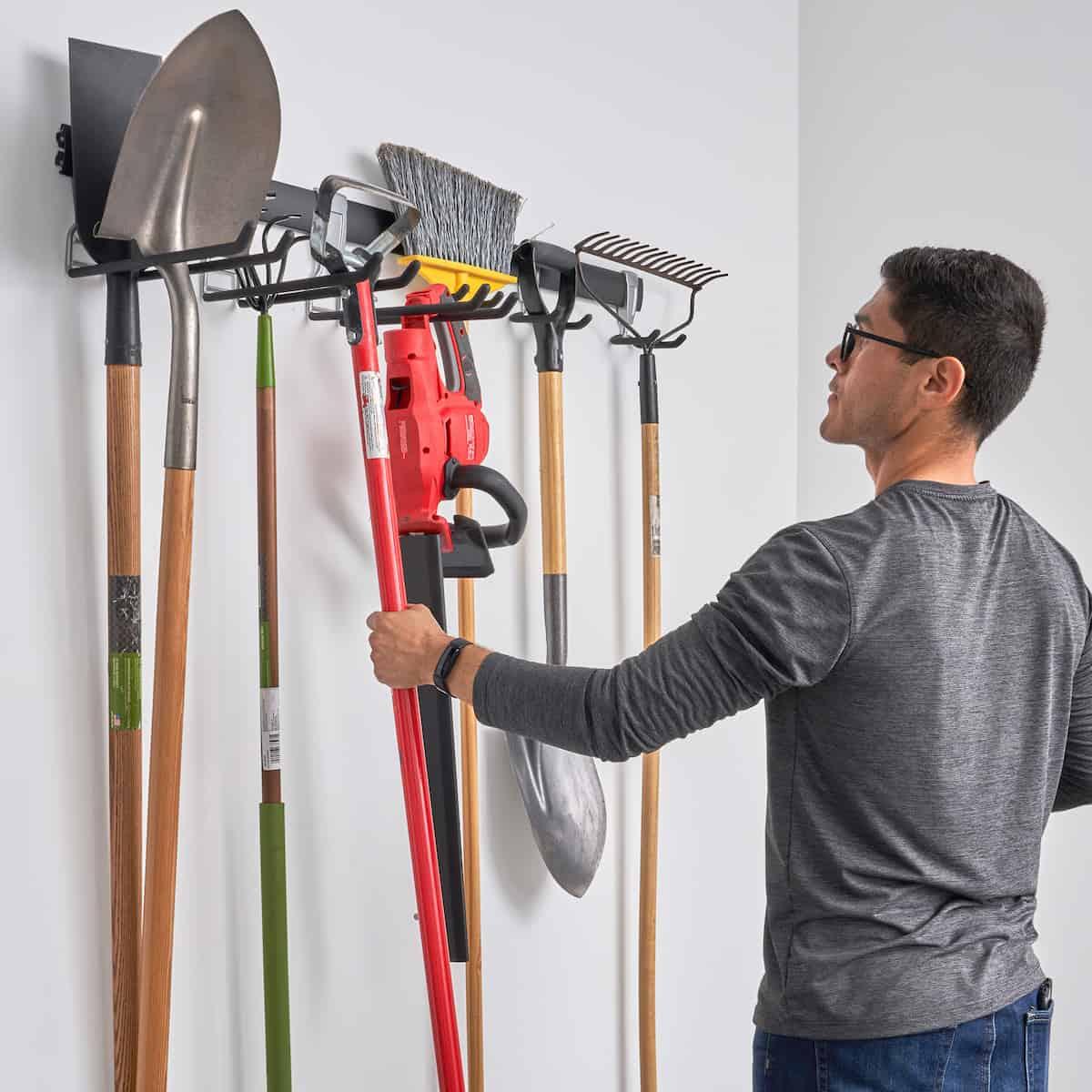 Person hanging shovel on garage wall track system