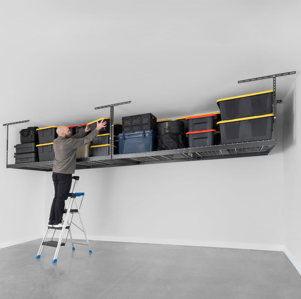 person removing storage bin from a saferacks overhead garage storage rack loaded with storage bins, boxes, and coolers