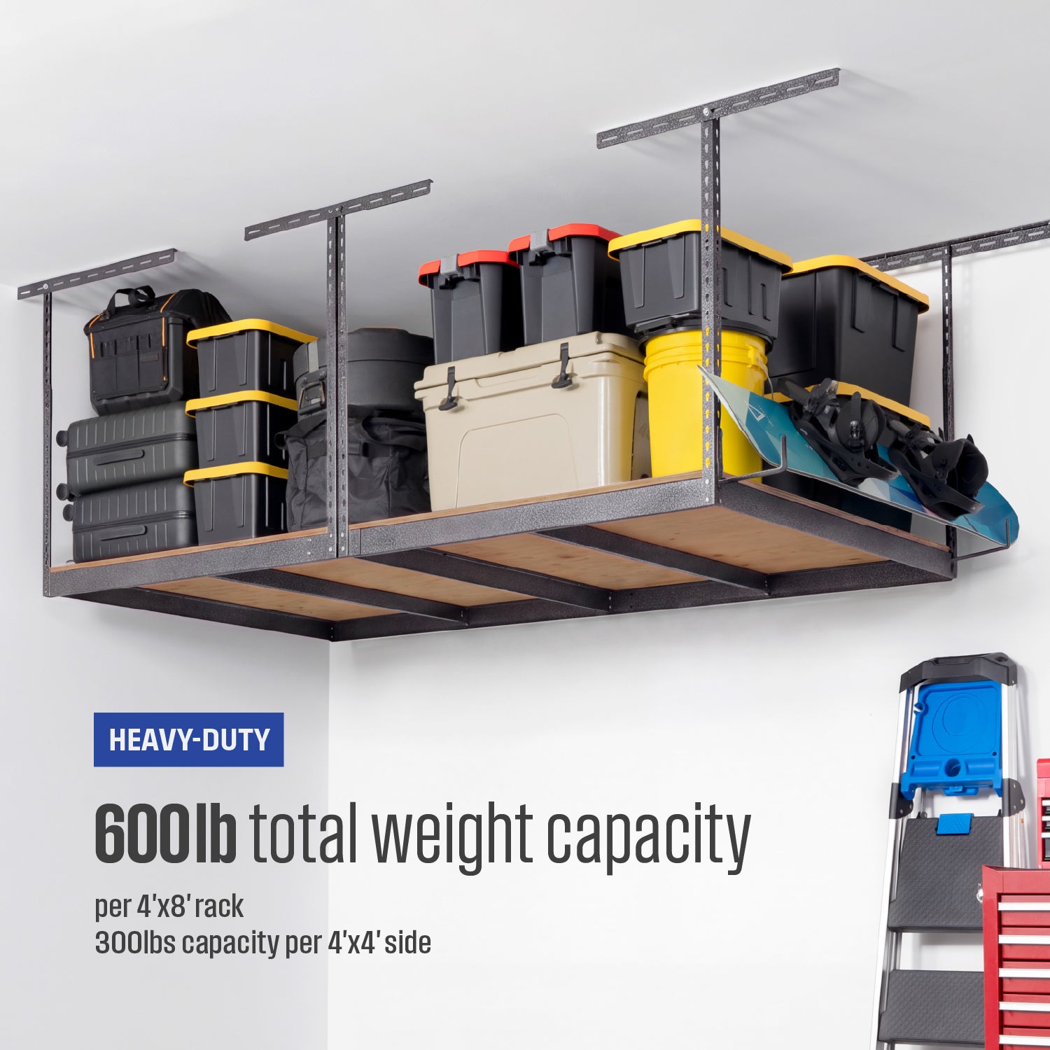 An overhead garage storage rack filled with storage bins and gear. Text below reads 'Heavy-Duty 600lb total weight capacity per 4'x8' rack. 300lbs capacity per 4'x4' side"