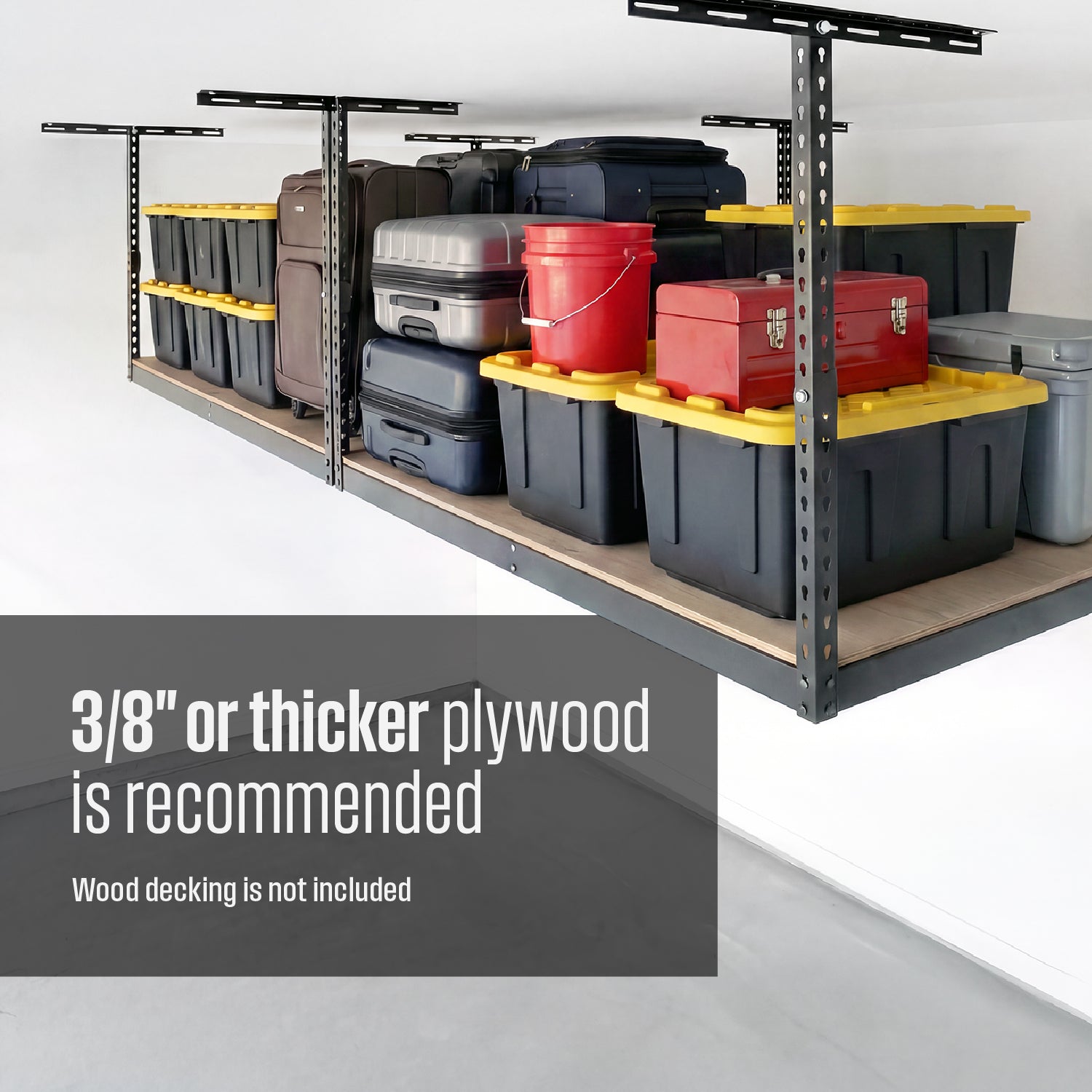 An overhead storage rack with plywood decking filled with storage bins, suitcases, and garage gear. Text overlay reads "3/8 inch of thicker plywood is recommended, wood decking is not included"