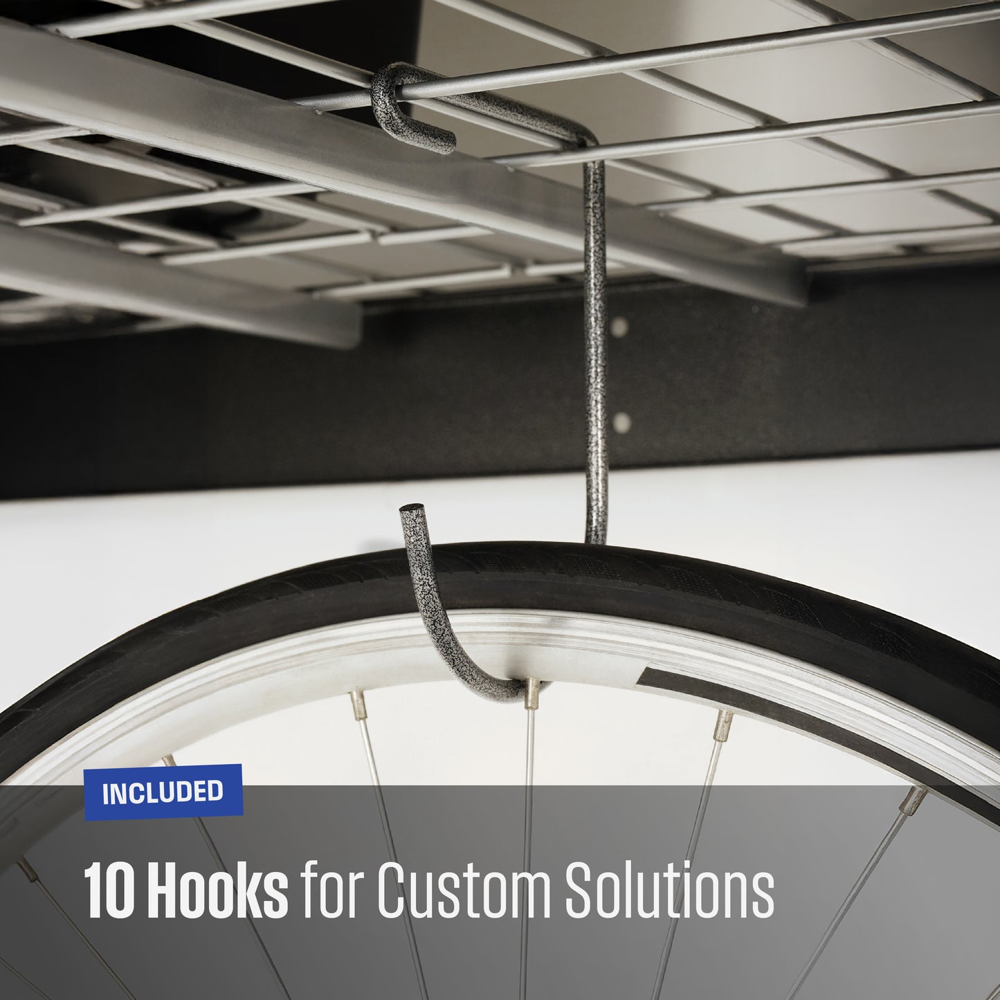 Close-up of a textured grey metal hook hanging from a garage shelf, with a bicycle tire partially visible to demonstrate use. Text overlay reads 'INCLUDED 10 Hooks for Custom Solutions'.