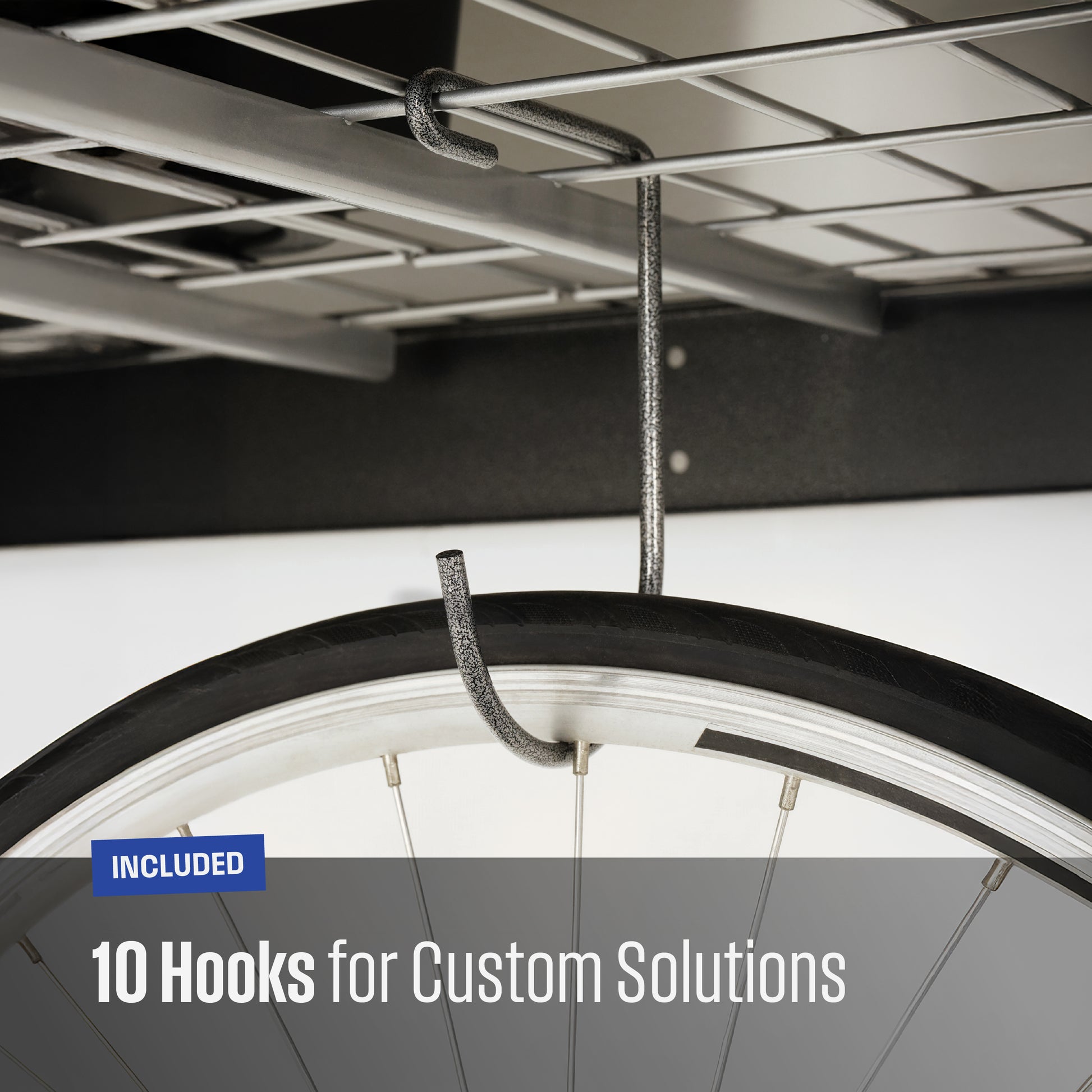 Close-up of a textured grey metal hook hanging from a garage shelf, with a bicycle tire partially visible to demonstrate use. Text overlay reads 'INCLUDED 10 Hooks for Custom Solutions'.