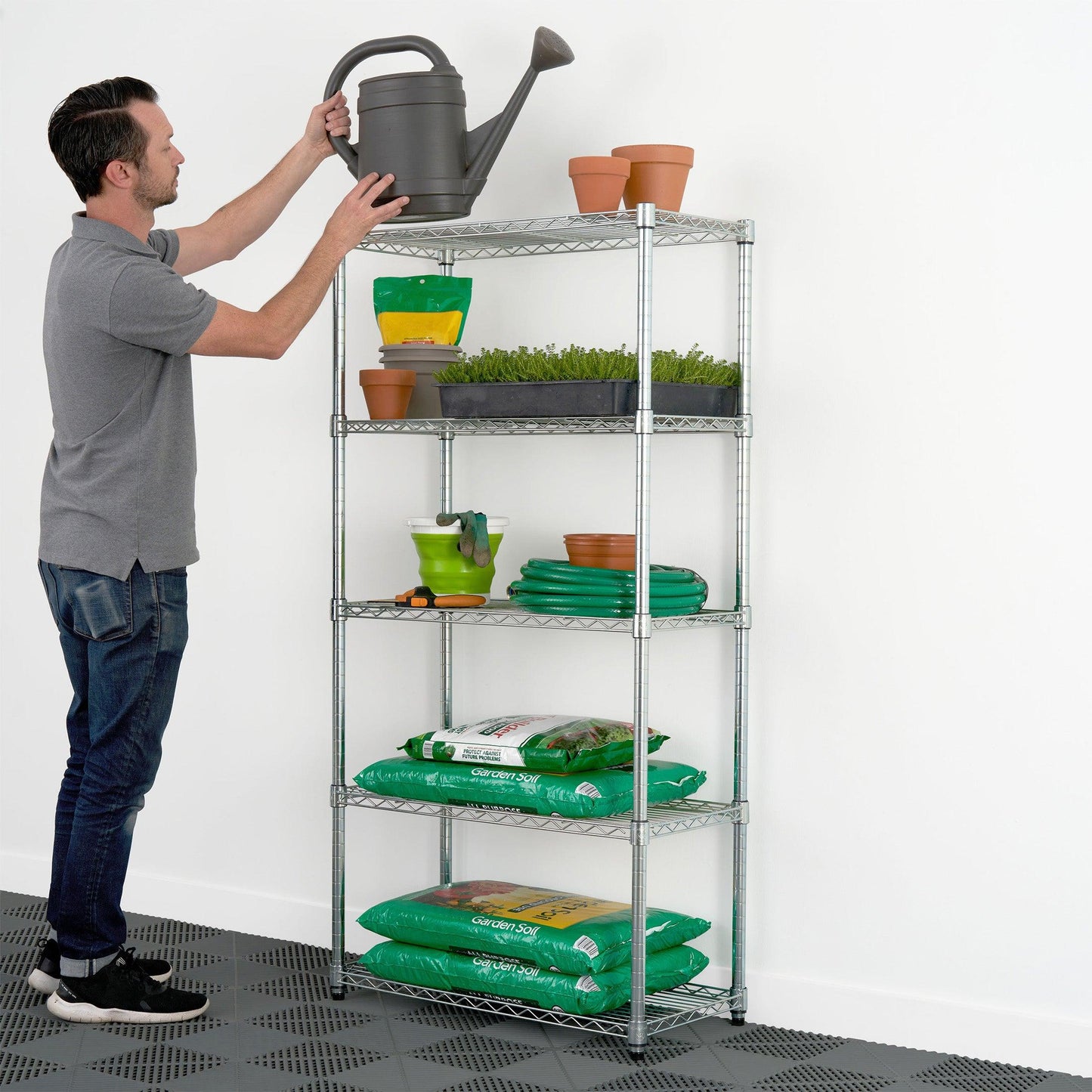 Person storing garden equipment on 14" x 30" x 60" Wire Shelving Rack 