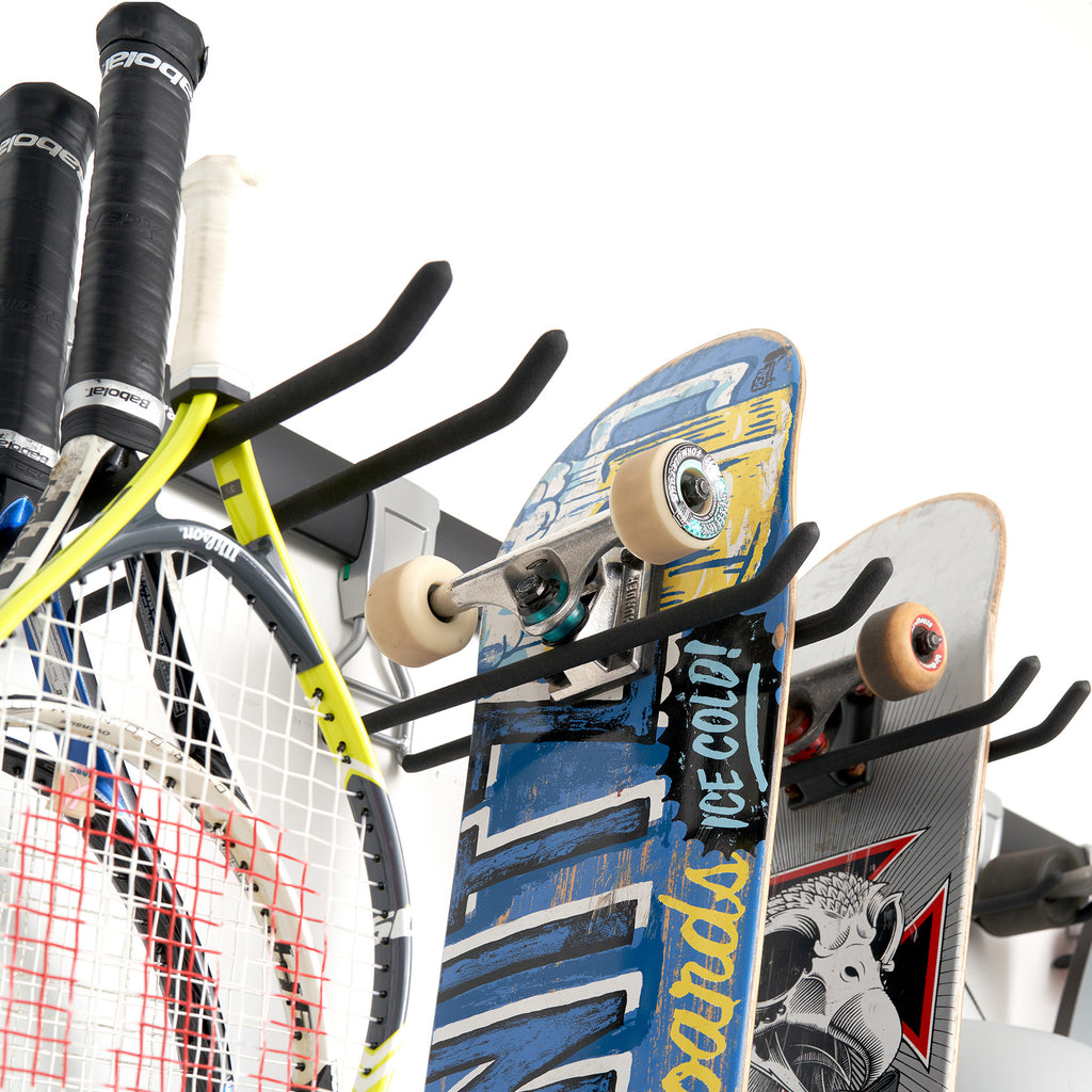 garage track system with adjustable hooks loaded with skateboards, and tennis rackets