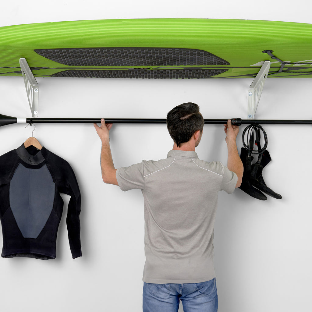 person removing paddle from surfboard rack