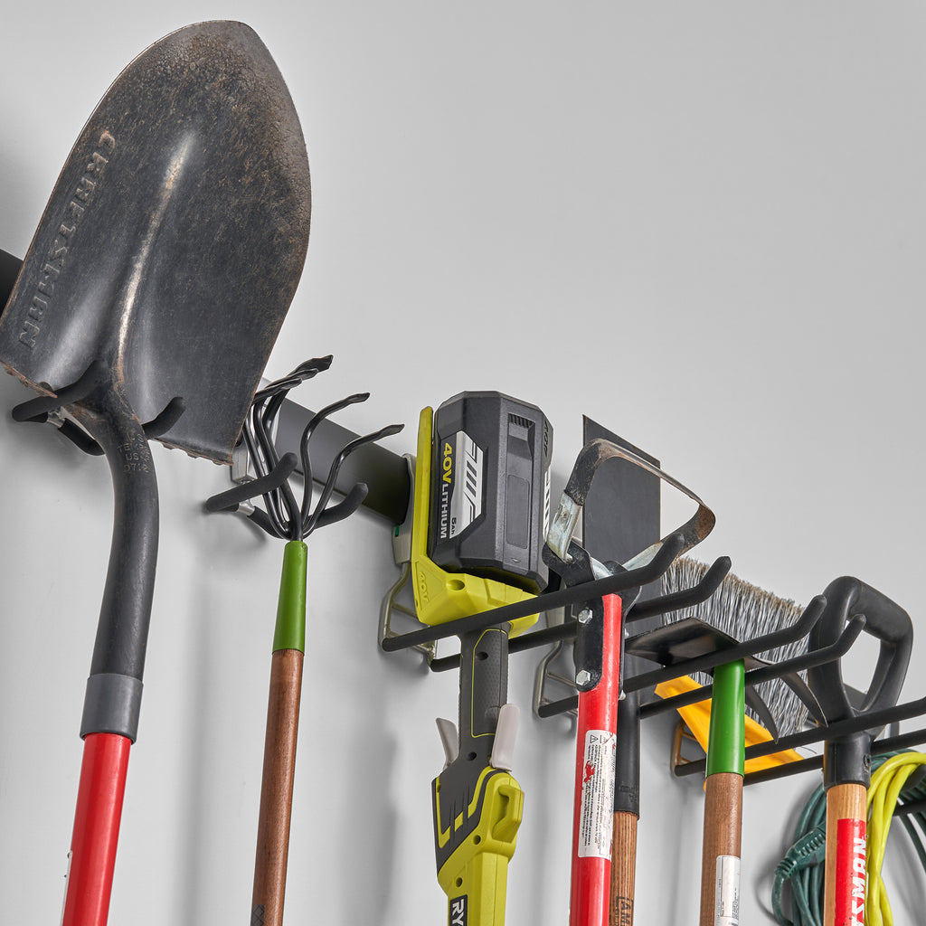 garage track system with adjustable hooks loaded with shovels, rakes, and gardening equipment